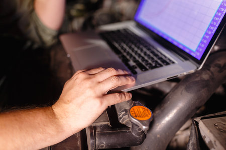 Closeup hands of mechanic with the help of diagnostic machines is ready for use with the car. Laptop...