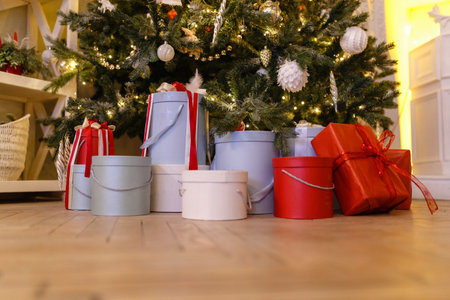 Christmas gifts under the tree on the wooden floor in the living room. A variety of gift boxes decorated with bows on the background of the Christmas tree.の写真素材