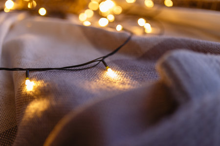 Close - up of garland with yellow lights. Cozy winter or autumn morning at home, warm blanket,の写真素材