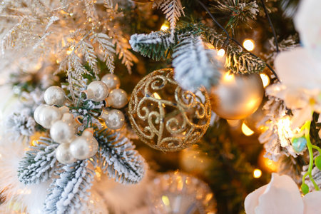 Gold decorations Christmas toys on the Christmas tree. Garland with bright yellow lights in...
