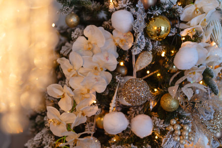 Gold decorations Christmas toys on the Christmas tree. Garland with bright yellow lights in artificial snow.の写真素材