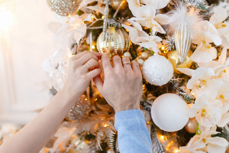Young couple decorates the Christmas tree. Merry Christmas and happy New year!. A young couple celebrates the holiday at home.の写真素材