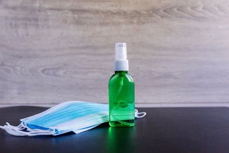 Coronavirus protective equipment - medical protective mask and green antiseptic disinfectant spray. Medical mask hand sanitizer. Prevention of covid-19 medical masks and hand sanitizer sprayの写真素材