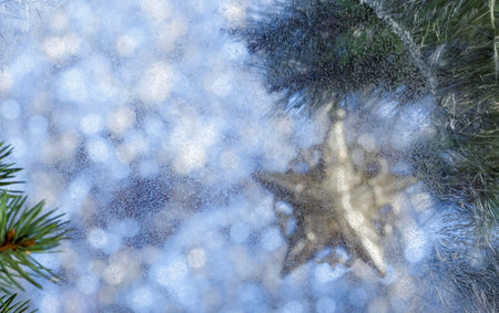 Christmas background. Blurred background. Frosty pattern on the window. Fir branch outside the...