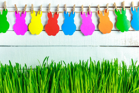 Green grass on wooden background. A lovely garland of bunnies. Place for Your text. Easter card....