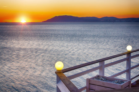 Sea sunset. View from the beach restaurant. Meeting of the sunset. Sea, mountains, solitude.の写真素材
