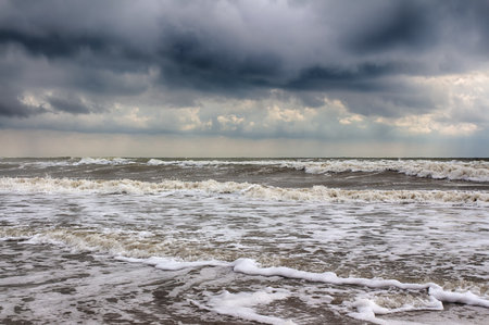 Sea storm. The waves break on the sandy beach. Tragic sky.の写真素材