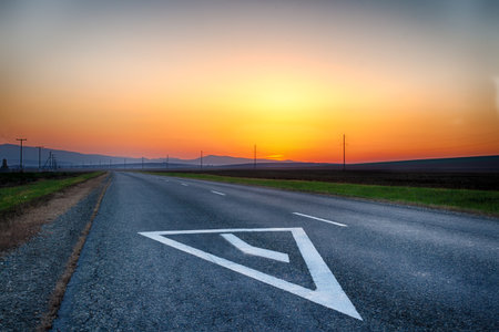 Mountain road. The curve of the road at sunset. Asphalt coating. Bright horizon.の写真素材