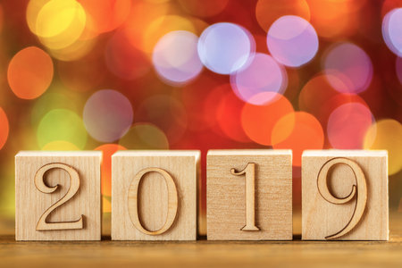 Christmas card, wooden cubes on the background of bokeh. Catchy bright design. Happy new year 2019.の写真素材