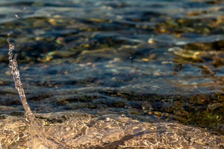 Splash of sea water. Clear sea, the play of light in the droplets. Glare and blurred background.の写真素材
