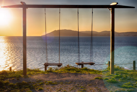 Rope swing at sunset. A place of romantic encounters. Swing on cliff. Setting sun. Seascape.