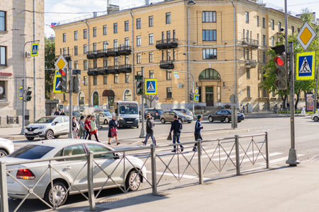 Saint Petersburg Russia 28.05.2021 pm 19.00. The intersection of Revolution Highway and Sredneokhtinsky Prospekt. A group of people crosses the road at a green traffic light.のeditorial素材