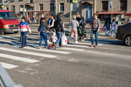Saint Petersburg Russia 28.05.2021 pm 19.00. The intersection of Revolution Highway and Sredneokhtinsky Prospekt. A group of people crosses the road at a green traffic light.のeditorial素材
