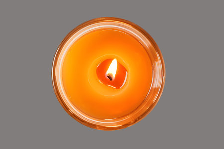 Burning candle in a glass candlestick on a gray backgroundの素材