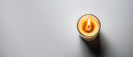 Burning candle in a glass on a gray background, top viewの素材