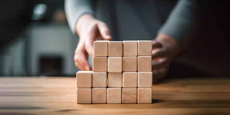Close-up of man stacking wooden cubes on table at home, panoramaの素材