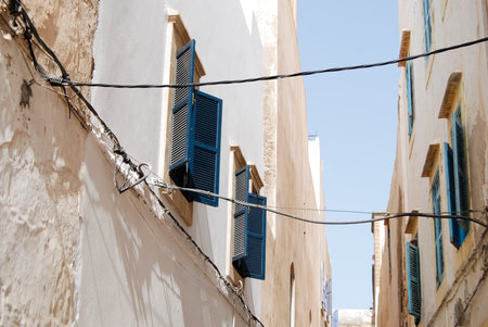 Sky sunlight view from the street of medina with traditional buildings, window with blue shutter, pastel colorsの写真素材