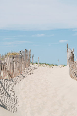 Entrance to a beach with wood fence, sand and blue sky, Cape Codの写真素材