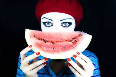 Portrait of the mime on a black background with a water-melon pieceの写真素材