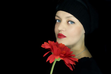 young girl with a red flower on a black backgroundの写真素材