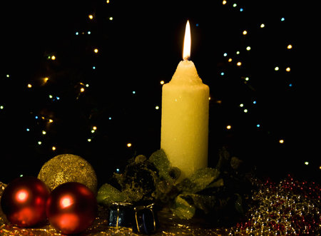 Burning candle with Christmas-tree decorations against a dark backgroundの写真素材