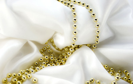 Gold beads on white silkの写真素材
