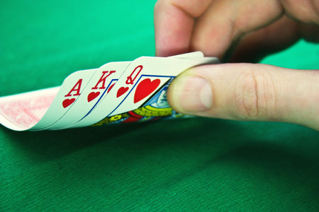 Playing cards and fingers on a green background