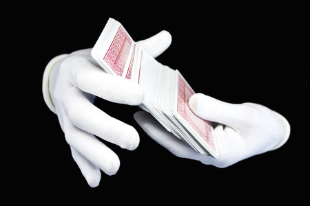 Hands in white gloves with a pack of playing cards on a black backgroundのeditorial素材