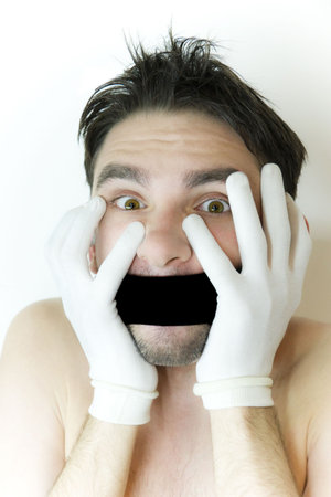 scared young man in white gloves  with  bandage on  mouthの写真素材