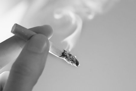 Fingers with a smoking cigaretteの写真素材