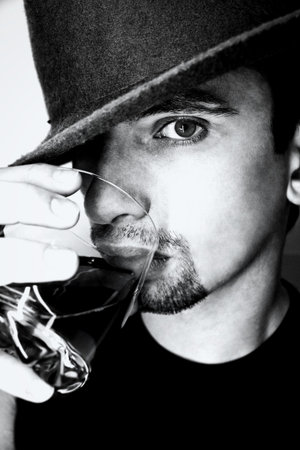 Portrait of young man in  hat with  glass of whisky 