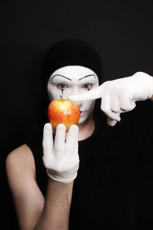Mime with red apple on White gloves against  black backgroundの写真素材