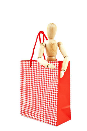 little wooden man in  red gift bags isolated on a white backgroundの写真素材