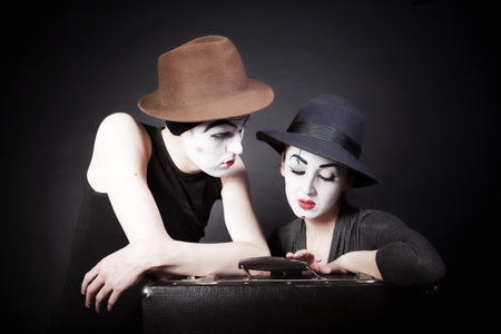 Two mimes man and  woman in hats with a suitcase on  black backgroundの写真素材