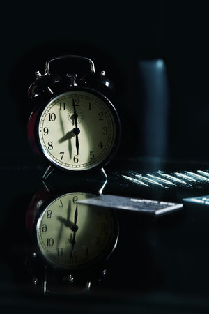 Alarm Clock, strip cocaine and credit cards on a glass table close up