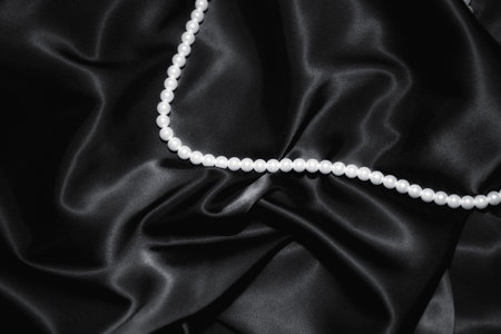 white pearl necklace on a black silk close upの写真素材
