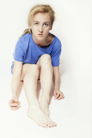 Fair-haired beautiful woman in blue shirt sitting on floorの写真素材