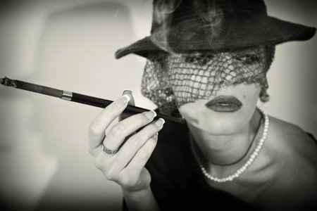 Young beautiful woman with  cigarette in mouthpiece in hat with veil の写真素材