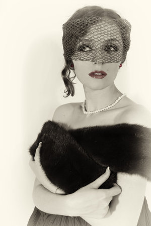 Retro portrait of young beautiful woman in veil and mink shawl with pearls on white backgroundの写真素材