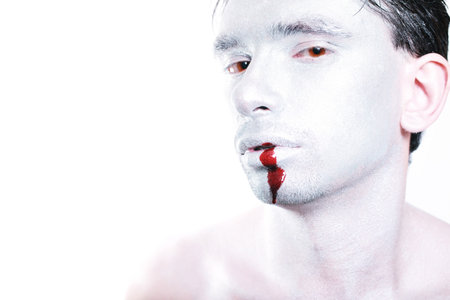 young man with silver makeup and blood on her mouthの写真素材