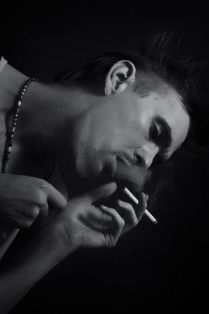 young man smoking cigarette on black backgroundの写真素材