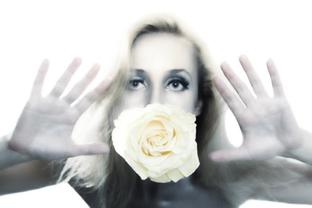 Young beautiful woman with silver make-up holding flower of white roses in his mouthの写真素材