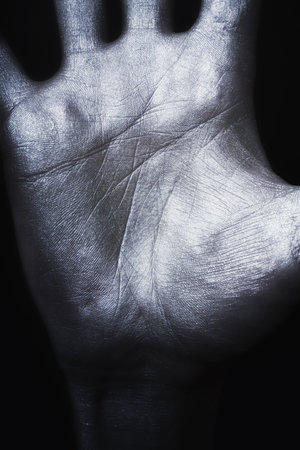 Man's hand in silver paint on  black background closeupの写真素材