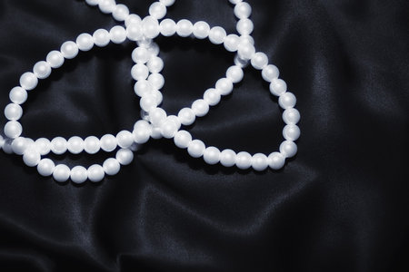 white pearl necklace on a black silk close upの写真素材