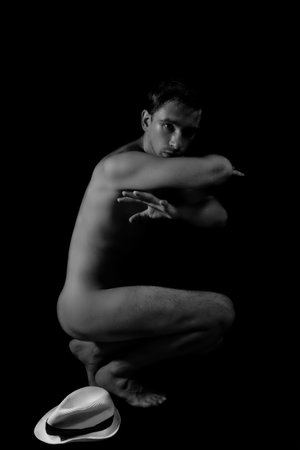 Young beautiful tanned naked dancer with white hatの写真素材
