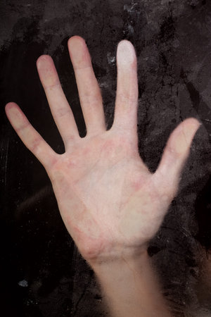 Hand pressed against dirty wet glass closeの写真素材
