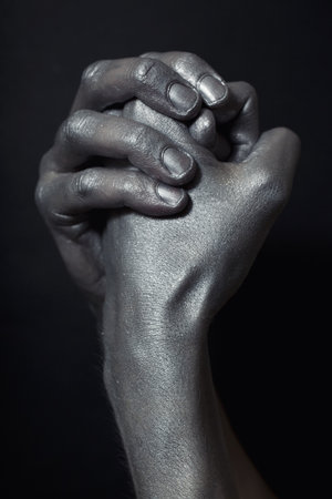 beautiful male hands in silver paint on  black backgroundの写真素材