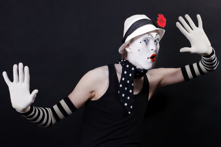 Funny mime in white hat with red flower on a black backgroundの写真素材
