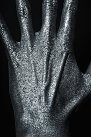 Man's hand in silver paint on black background closeupの写真素材