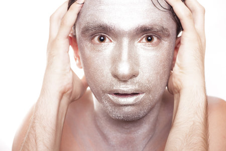 face of young man with frightened eyes and bronzed makeup close upの写真素材